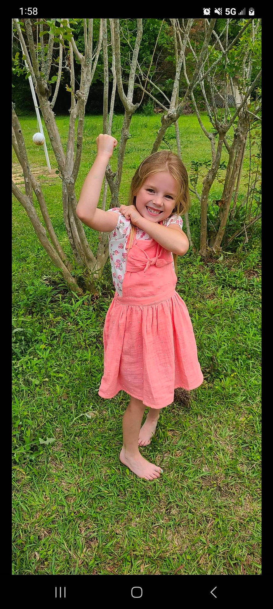 Vivian is registered to the contest to win money with this photo: baby_toddler_clothing, child, day_dress, dress, face, gesture, grass, happy, joy, magenta, one_piece_garment, pattern, people_in_nature, person, plant, sleeve, smile, spring, summer, toddler