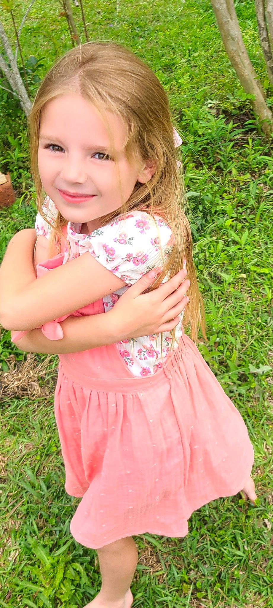 Vivian is registered to the contest to win money with this photo: baby_toddler_clothing, child, day_dress, dress, eye, gesture, grass, hair, happy, iris, joy, lip, long_hair, pattern, people_in_nature, person, pink, plant, skin, smile