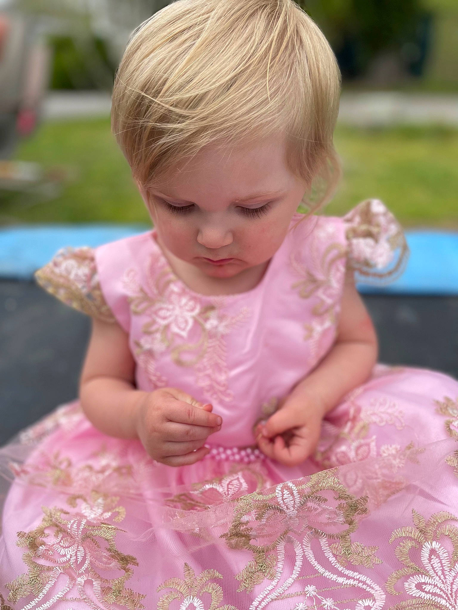 Olivia joined the competition — help win amazing prizes! baby_toddler_clothing, blond, child, dress, embellishment, event, face, facial_expression, fun, grass, hairstyle, happy, magenta, people, person, pink, ruffle, sitting, skin, summer