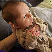 Matteo joined the competition — help win amazing prizes! baby, newborn, infant, person, face, eye, hands, fingers, onesie, clothing, blanket, bed, parent_hand, tattoo, closeup, soft_light, indoor, portrait, cozy, sleepy