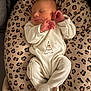 baby, newborn, sleeping, onesie, animal_print, cushion, leopard_print, soft_lighting, infant, cozy, cute, peaceful, portrait, child, resting, indoor, plush, white_clothing, hands, face