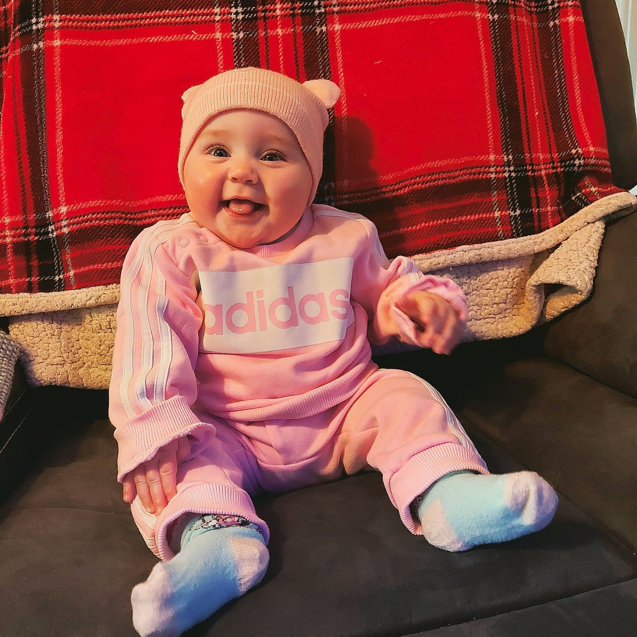 Cara joined the competition — help win amazing prizes! baby, baby_products, baby_toddler_clothing, cap, child, comfort, happy, hat, head, headwear, lap, linens, magenta, outerwear, pattern, person, plaid, sitting, sleeve, smile