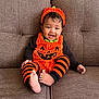 baby, child, pumpkin_costume, orange, black, striped_leggings, headband, smiling, sitting, couch, furniture, indoors, cute, happy, portrait, holiday, halloween, costume, person, infant