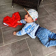 Andrea participe au concours pour gagner de l'argent avec cette photo : baby, child, cap, blue_jeans, sweater, dinosaur_print, red_bag, floor_tiles, wicker_chair, sneaker, indoor, crawling, happy, smiling, person, clothing, footwear, playful, young_child, casual