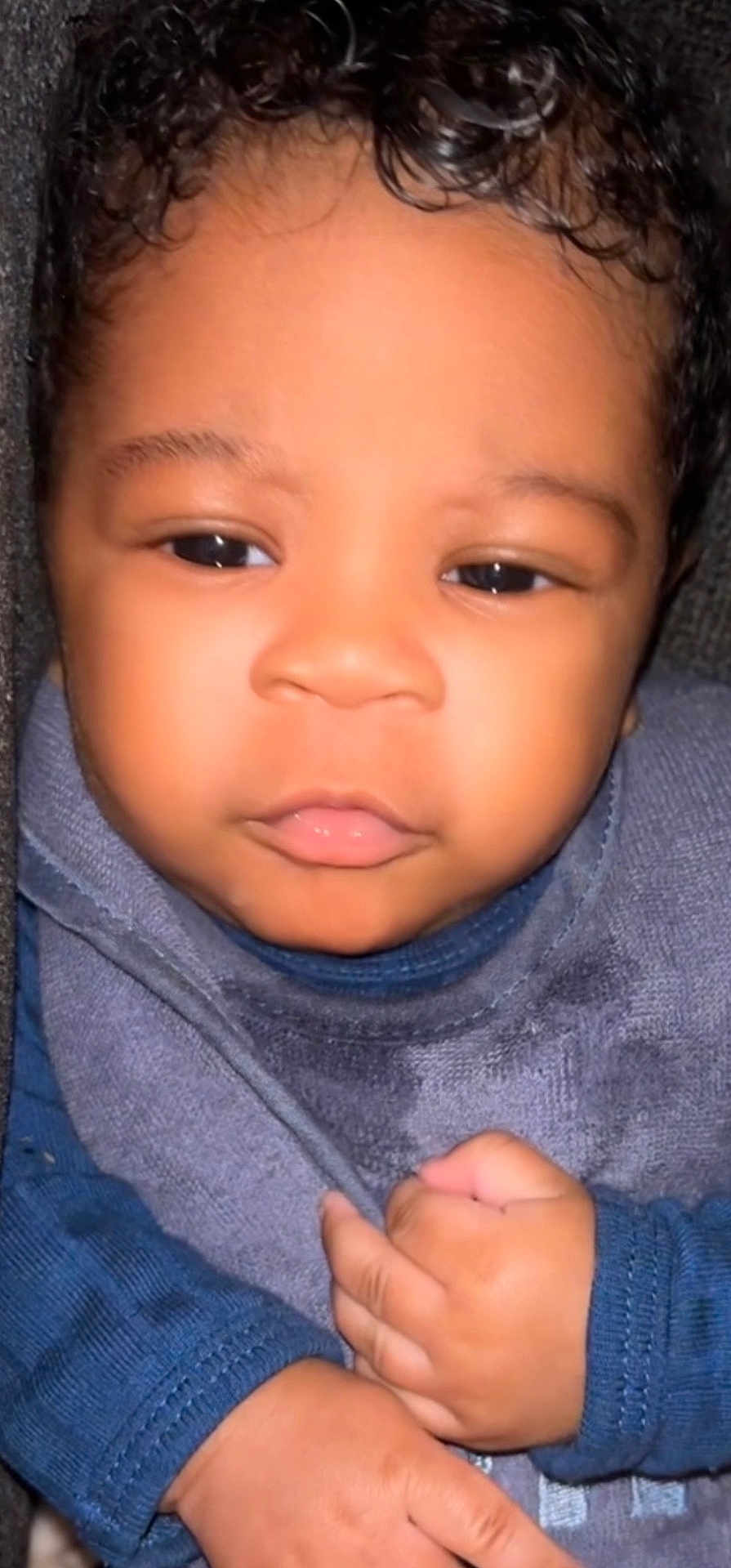 Austin Carter is registered to the contest to win money with this photo: baby, close_up, child, infant, face, hands, curly_hair, blue_clothing, bib, cute, portrait, skin, young, person, expression, indoors, soft_light, texture, calm, small_hands