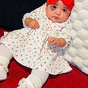 Catalina joined the competition — help win amazing prizes! baby, infant, child, red_bow, headband, white_dress, floral_pattern, white_tights, white_shoes, pillow, blanket, red_blanket, indoor, cute, portrait, lying_down, soft_texture, adorable, young, fashion