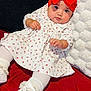 baby, infant, child, red_bow, headband, white_dress, floral_pattern, white_tights, white_shoes, pillow, blanket, red_blanket, indoor, cute, portrait, lying_down, soft_texture, adorable, young, fashion
