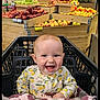 baby, shopping_cart, grocery_store, fruit, apples, produce_section, smile, child, infant, clothing, pattern, lemon, happy, retail, market, wooden_display, fresh, food, indoor, person