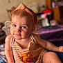 toddler, child, headband, striped_clothing, sitting, indoor, portrait, cute, baby, person, face, smiling, soft_focus, furniture, hand, legs, orange, pink, skin, expression