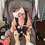 Maeve joined the competition — help win amazing prizes! baby, stroller, bow, heart_pattern, scarf, toy, soft_toy, pink, white_shoes, infant, seated, indoor, curious, child, clothing, safety_harness, cute, person, headwear, baby_accessory