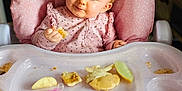 Elodie is registered to the contest to win money with this photo: baby, child, high_chair, pink, food, snack, crumbs, pacifier, face, blue_eyes, clothing, cute, infant, table, feeding, indoor, person, seat, happy, messy