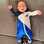 baby, blue_jumpsuit, casual_wear, child, clothing, couch, cute, face, footwear, home_interior, indoors, infant, lying_down, nike, person, shoes, sneakers, socks, stretching, young