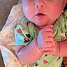 baby, infant, child, portrait, close_up, wide_eyed, hands_clasped, floral_clothing, green_outfit, blanket, fox_pattern, lying_down, indoor, cozy, face, eyes, head, bare_arms, baby_clothing, photography