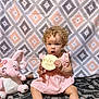 toddler, child, curly_hair, pink_dress, plush_toy, elephant_toy, carpet, patterned_blanket, baby, sitting, indoor, holding_sign, nine_months, cute, portrait, young_child, floor, smiling_toy, curly_hair_baby, infant