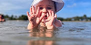 Demi is registered to the contest to win money with this photo: child, toddler, water, hat, hands, mud, outdoor, sky, nature, playful, summer, sunhat, shallow_water, reflection, person, daylight, happy, fun, young_child, blue_sky