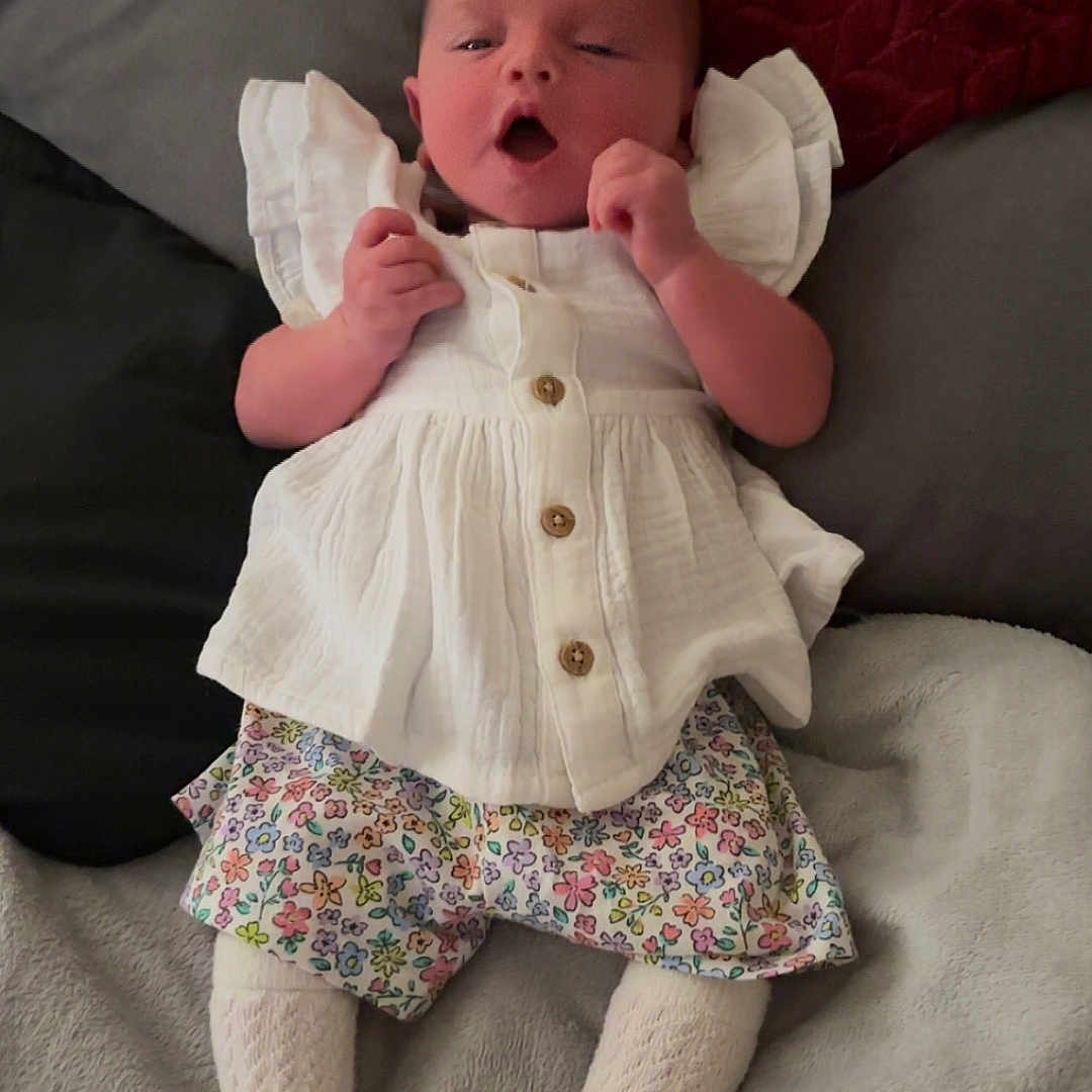 Harper is registered to the contest to win money with this photo: baby, bodypart, clothing, couch, cushion, face, finger, furniture, hand, hat, head, hosiery, pants, person, photography, portrait, shorts, skirt, sock, toy