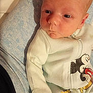 Leo is registered to the contest to win money with this photo: baby, infant, child, mickey_mouse, clothing, onesie, blanket, fabric, person, face, head, skin, cute, young, lying_down, indoor, portrait, newborn, expression, soft