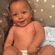 Mateo joined the competition — help win amazing prizes! baby, infant, diaper, smiling, face, cute, child, plush_toy, cushion, patterned_fabric, star_pattern, bare_skin, happy, sitting, indoors, soft_blanket, playful, chubby, portrait, comfort
