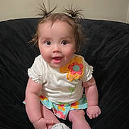 Birdie joined the competition — help win amazing prizes! baby, child, infant, sitting, smiling, white_shoes, flower_pattern, colorful_clothing, pigtails, cute, happy, indoors, black_chair, plush, person, young_child, casual, portrait, fun, playful