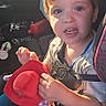 Alixx is registered to the contest to win money with this photo: child, toddler, car, car_seat, seatbelt, plush_toy, red_toy, portrait, indoors, vehicle, sunlight, brown_hair, blue_eyes, looking_at_camera, sitting, travel, automobile_interior, casual_clothing, toy,  안전