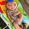 arm, baby, baby_clothing, blue_cup, child, colorful_baby_rocker, cute, distorted_face, expression, face, footwearless, funny, hat, indoors, infant, person, plastic, sitting, toy_pattern, wooden_floor