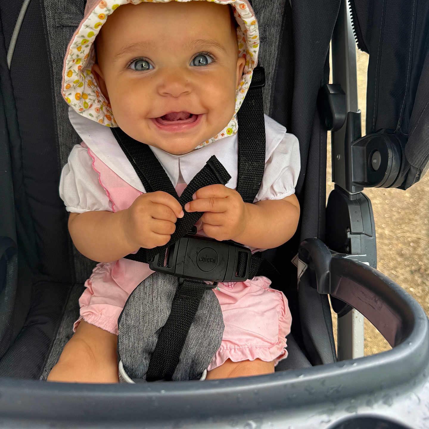 Gabriella joined the competition — help win amazing prizes! baby, baby_girl, blue_eyes, bonnet, child, closeup, cute, hands, happy, headwear, infant, outdoor, person, pink_clothing, portrait, seatbelt, sitting, smiling, stroller, toy