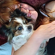 Jenna is registered to the contest to win money with this photo: person, dog, face, hair, arm, closeup, cuddle, pet, animal, furry, smile, skin, red_hair, lying_down, comfort, affection, indoors, portrait, relaxation, companionship