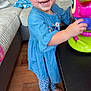 toddler, child, smiling, blue_dress, floral_leggings, barefoot, toy, living_room, couch, wooden_floor, happy, person, indoor, playful, furniture, table, cute, young_child, portrait, home