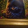 painting, dog, black_fur, fluffy, portrait, framed_art, wooden_frame, green_leaves, pink_flowers, smiling, eyes, fur_texture, artwork, illustration, decor, indoor, closeup, animal_portrait, background, nature_elements