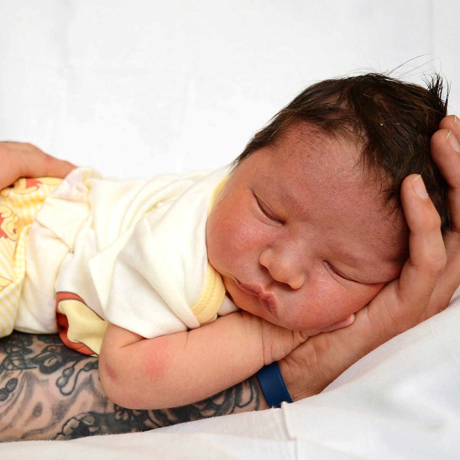 Waylon joined the competition — help win amazing prizes! newborn, baby, sleeping, tattoo, arm, hand, white_bedding, soft_light, peaceful, infant, clothing, yellow_pants, cute, portrait, resting, skin, closeup, child, parent, tender_moment