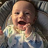 Jaxon is registered to the contest to win money with this photo: baby, smiling, infant, onesie, dinosaur_pattern, cushion, baby_seat, happy, child, indoor, portrait, cute, young_child, person, clothing, seat, expression, face, hand, light