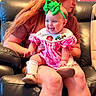 adult, baby, bib, child, farm_animals, green_bow, happy, headband, indoor, infant, lap, leather_couch, mother, pink_dress, portrait, shoes, smiling, socks, tractor, train