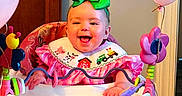 Macie is registered to the contest to win money with this photo: activity_walker, baby, baby_toys, balloons, bib, child, colorful, green_bow, happy, high_chair, home, indoor, infant, laughing, pink_clothing, playtime, portrait, sitting, smiling, wooden_door