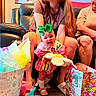 Macie is registered to the contest to win money with this photo: adults, baby, birthday, child, couch, dress, family, gift_bags, green_bow, happy, indoor, infant, living_room, man, portrait, smiling, stuffed_animal, tissue_paper, toy, woman