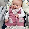 baby, child, infant, pink_dress, bunny_design, baby_chair, cushion, toy, stuffed_animal, smiling, cute, indoors, white_clothing, head_support, playful, small_hands, socks, comfort, happy, portrait