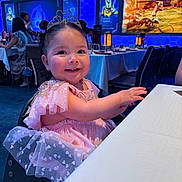 Zarali is registered to the contest to win money with this photo: toddler, child, smiling, princess_dress, tiara, pink, table, restaurant, indoor, people, happy, face, hair_buns, blue_lighting, decor, dining, seated, mickey_mouse, birthday, celebration