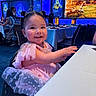 toddler, child, smiling, princess_dress, tiara, pink, table, restaurant, indoor, people, happy, face, hair_buns, blue_lighting, decor, dining, seated, mickey_mouse, birthday, celebration