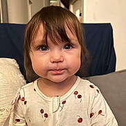 Olivia joined the competition — help win amazing prizes! toddler, child, face, eyes, hair, onesie, cherry_pattern, indoor, couch, pillow, curious, baby, portrait, young_child, clothing, cute, expression, soft_lighting, home, person