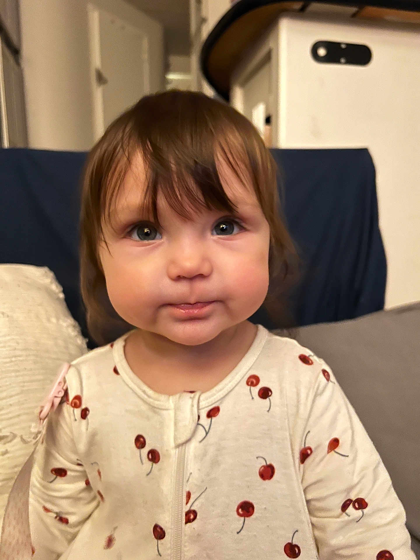 Olivia joined the competition — help win amazing prizes! toddler, child, face, eyes, hair, onesie, cherry_pattern, indoor, couch, pillow, curious, baby, portrait, young_child, clothing, cute, expression, soft_lighting, home, person