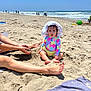 toddler, child, beach, sand, ocean, waves, sunhat, swimsuit, colorful_clothing, barefoot, adult_legs, hands, playing, summer, outdoor, sunny, sky, people, vacation, family