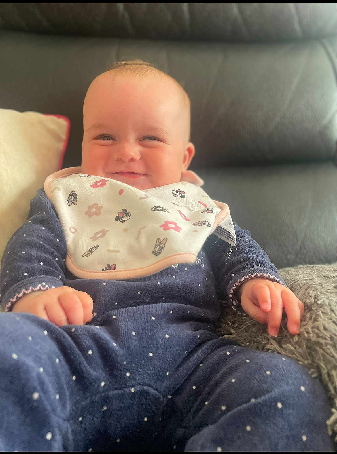 Mayana participe au concours pour gagner de l'argent avec cette photo : baby, smile, bib, blue_clothing, polka_dot, couch, leather, pillow, hand, face, infant, sitting, happy, indoors, child, young, cute, cozy, portrait, relaxed