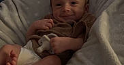Waylon is registered to the contest to win money with this photo: baby, infant, smiling, pacifier, cushion, blanket, brown_clothing, indoor, wooden_furniture, dresser, relaxed, comfort, soft_texture, child, person, face, happy, home, portrait, resting