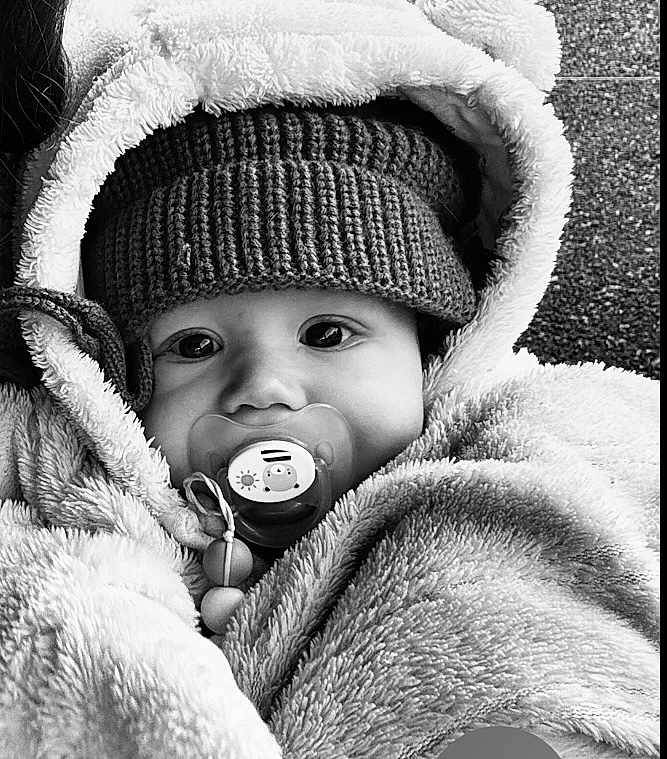 Antoine participe au concours pour gagner de l'argent avec cette photo : baby, child, pacifier, hat, hood, jacket, knitted, warm_clothing, black_and_white, portrait, face, cute, infant, bundle, soft_texture, close_up, winter_wear, young_child, expression, outdoor