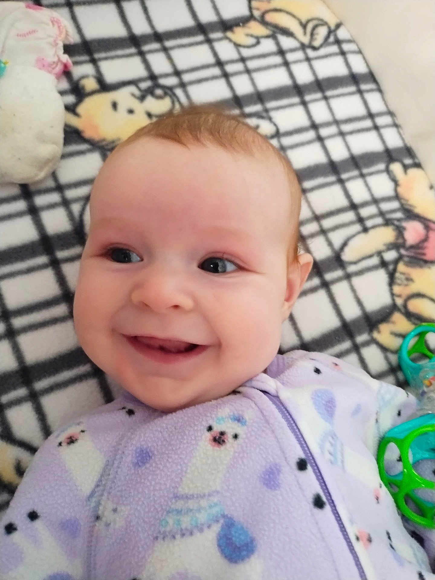 Shelby is registered to the contest to win money with this photo: baby, smiling, face, infant, blanket, toy, clothing, onesie, cute, happy, child, lying_down, indoor, closeup, head, expression, pattern, soft, playful, comfort