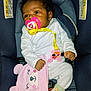 Jaylani is registered to the contest to win money with this photo: baby, infant, pacifier, car_seat, seat_belt, onesie, pink_hat, plush_toy, pacifier_clip, yellow_ribbon, hand, face, hair, blanket, buckle, warning_label, fabric, socks, toy, portrait