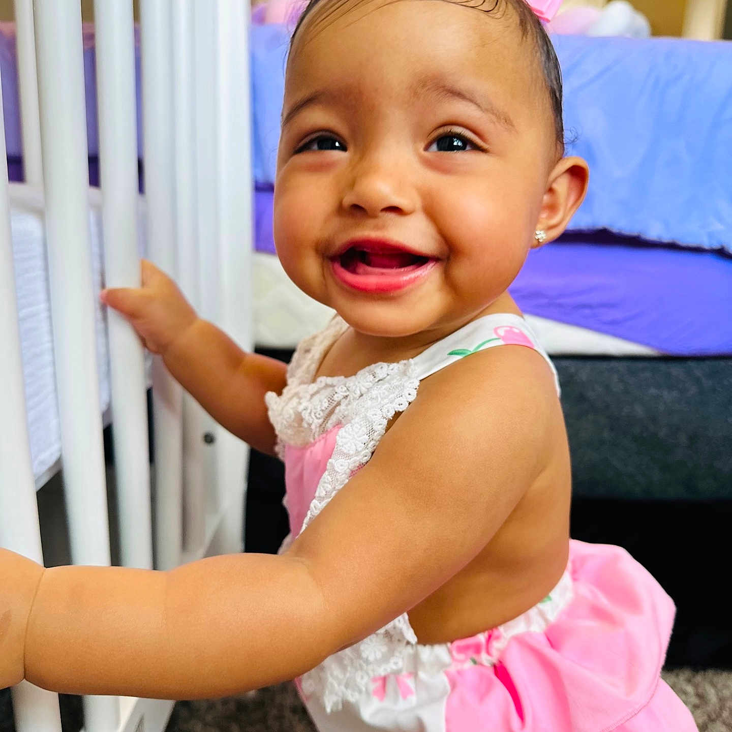 Kylie joined the competition — help win amazing prizes! baby, bed, carpet, child, clothing, crib, cute, face, furniture, happy, head, indoors, infant, person, pink_bow, playful, portrait, room, smiling, standing