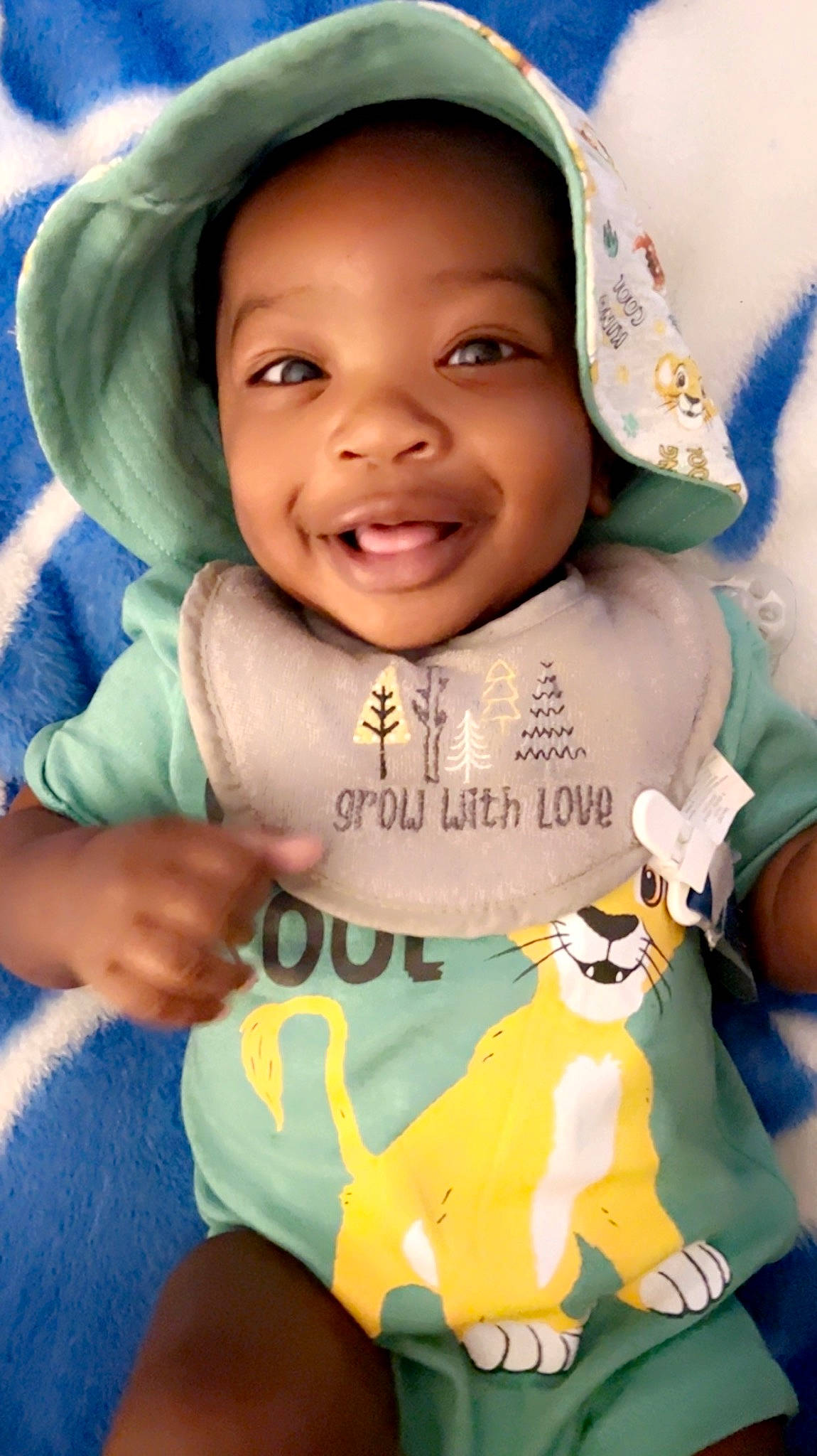 Andy is registered to the contest to win money with this photo: baby, baby_toddler_clothing, cheek, cool, facial_expression, finger, gesture, green, happy, headwear, joy, mouth, neck, nose, organ, person, product, skin, sleeve, smile