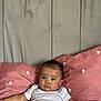 Aïtaynah a rejoint le concours — aidez-le/la à gagner de superbes lots ! baby, infant, child, white_clothing, pink_pillow, heart_pattern, headboard, bed, indoor, portrait, cute, chubby_cheeks, relaxed, looking_at_camera, soft_lighting, skin, hair, arms, lying_down, comfortable