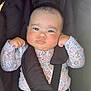baby, infant, car_seat, safety_harness, floral_clothing, cute, child, fist, serious_expression, pacifier, straps, black_background, indoors, skin, head, arms, legs, seat, person, one_person