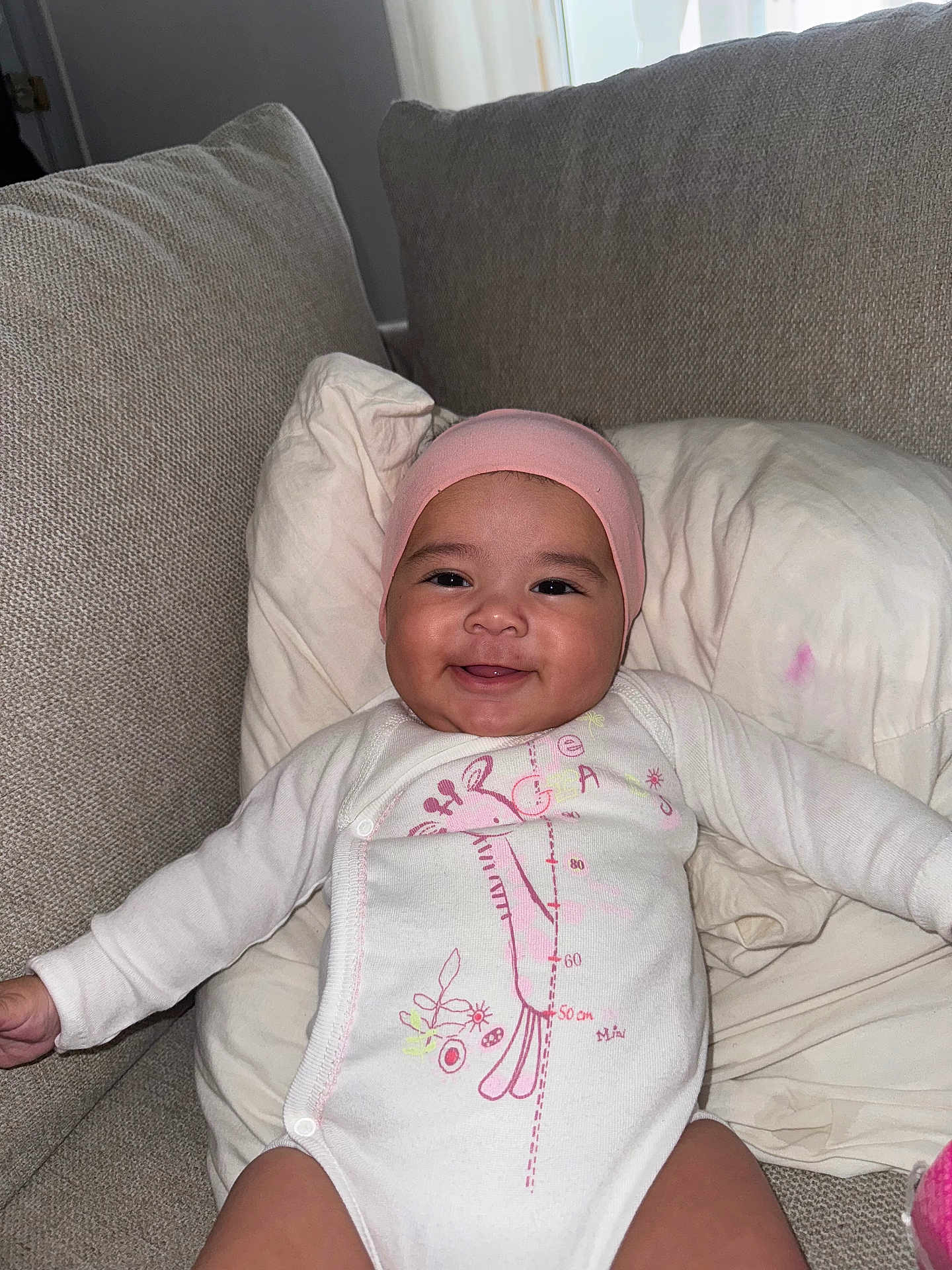 Aïtaynah participe au concours pour gagner de l'argent avec cette photo : baby, smiling, infant, pink_hat, white_onesie, giraffe_design, couch, pillow, indoors, child, happy, cute, person, portrait, sitting, fabric, cozy, home, young_child, relaxing